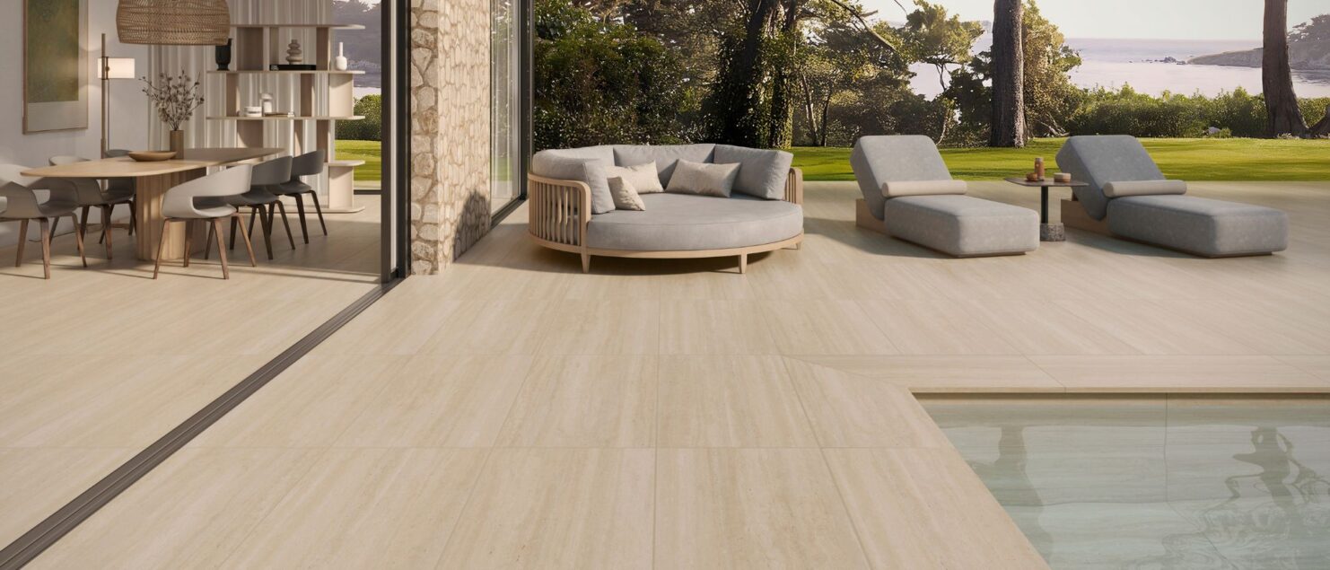 Salón moderno abierto a una terraza exterior con el mismo pavimento cerámico, creando continuidad visual In&Out.